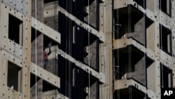 FILE - A worker uses a drill during construction of new apartment buildings in Beijing, China, Oct. 26, 2021.