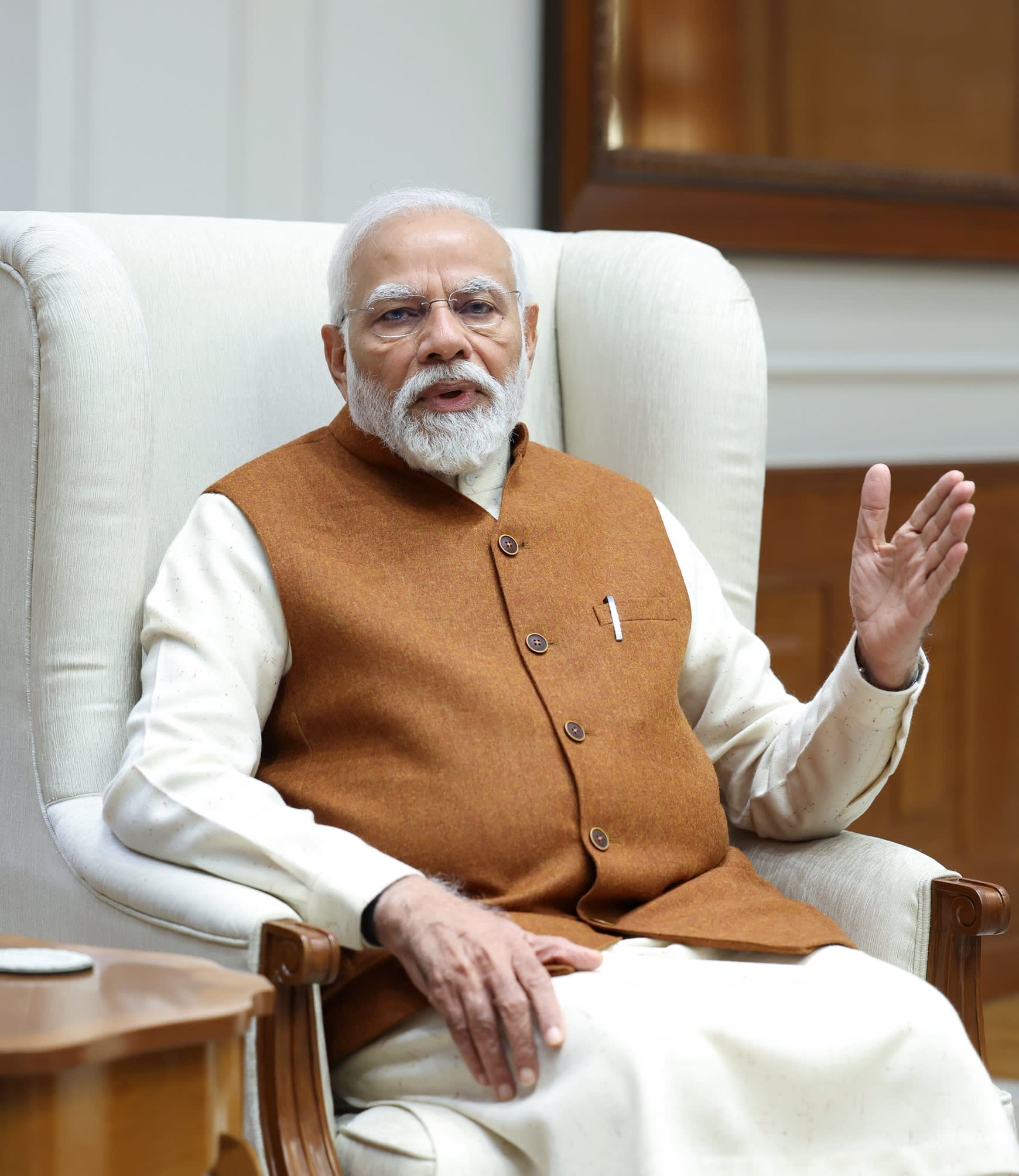 An Indian man in his early 70s sits in a cream-coloured chair 