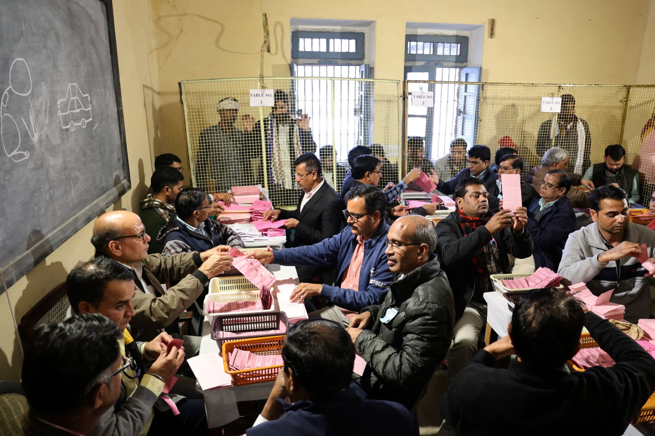 People count voter ballots in a crowded room