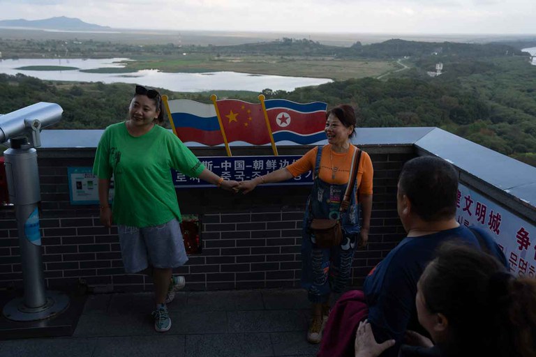 russia-north-korea-25.jpg Visitors hold hands near the Russia, China and North Korean flags displayed at China’s Yiyanwang Three Kingdoms viewing platform, which has a view of the three countries, Sept. 11, 2023. Credit: Ng Han Guan/AFP