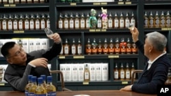 In this image from a video, Raymond Lee, founder of Single Malt Club China, right, samples whisky at a whisky store in Beijing on Dec. 9, 2023.