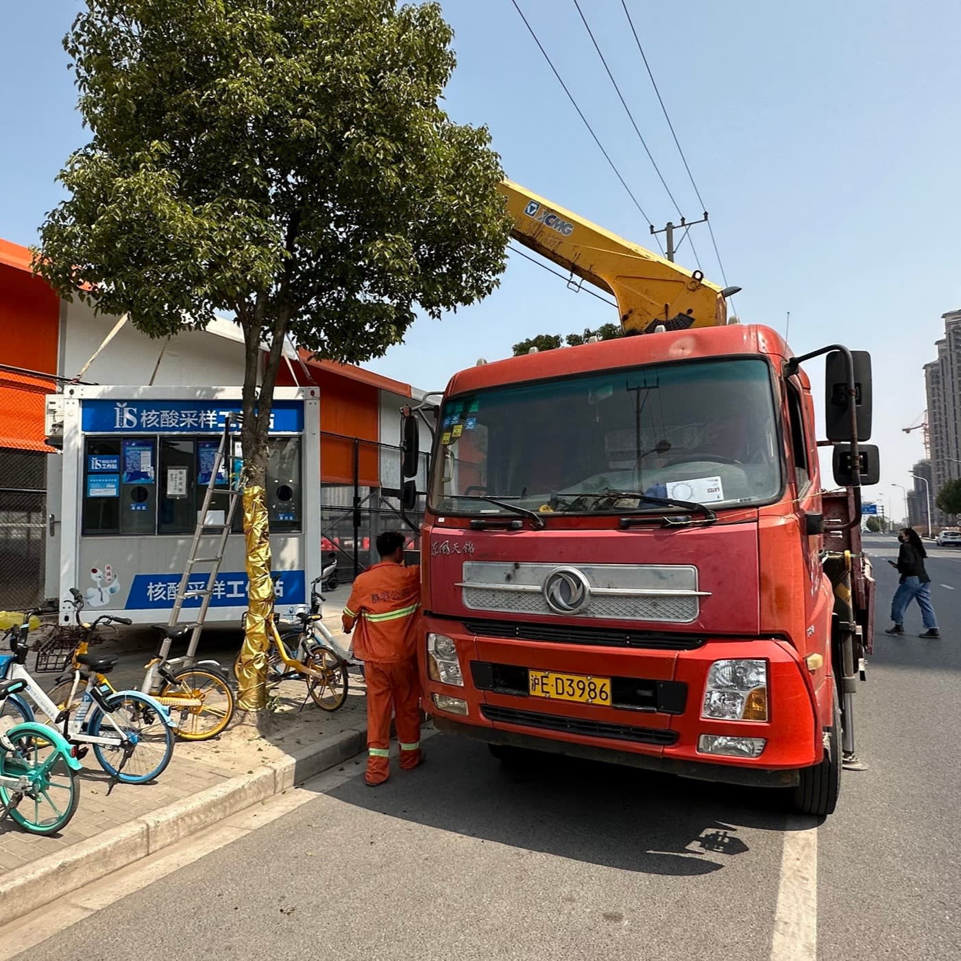 A truck’s crane lifts a cabin off the street