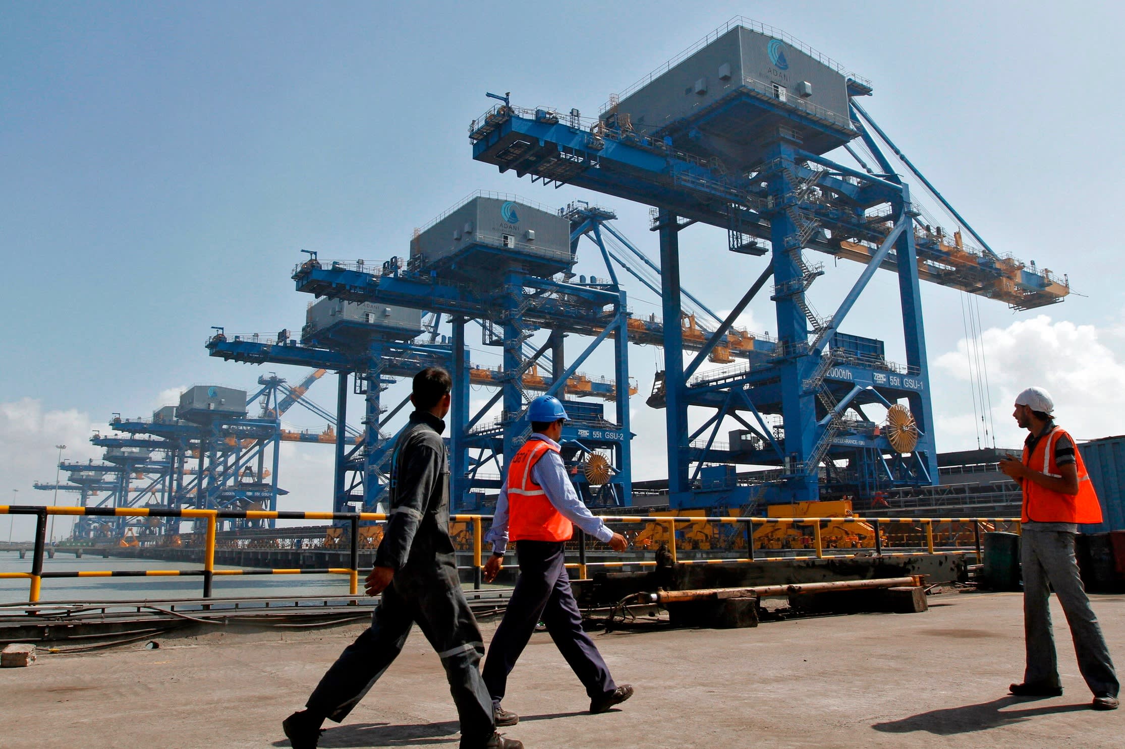 Workers walk past a coal port at Mundra in the western Indian state of Gujarat