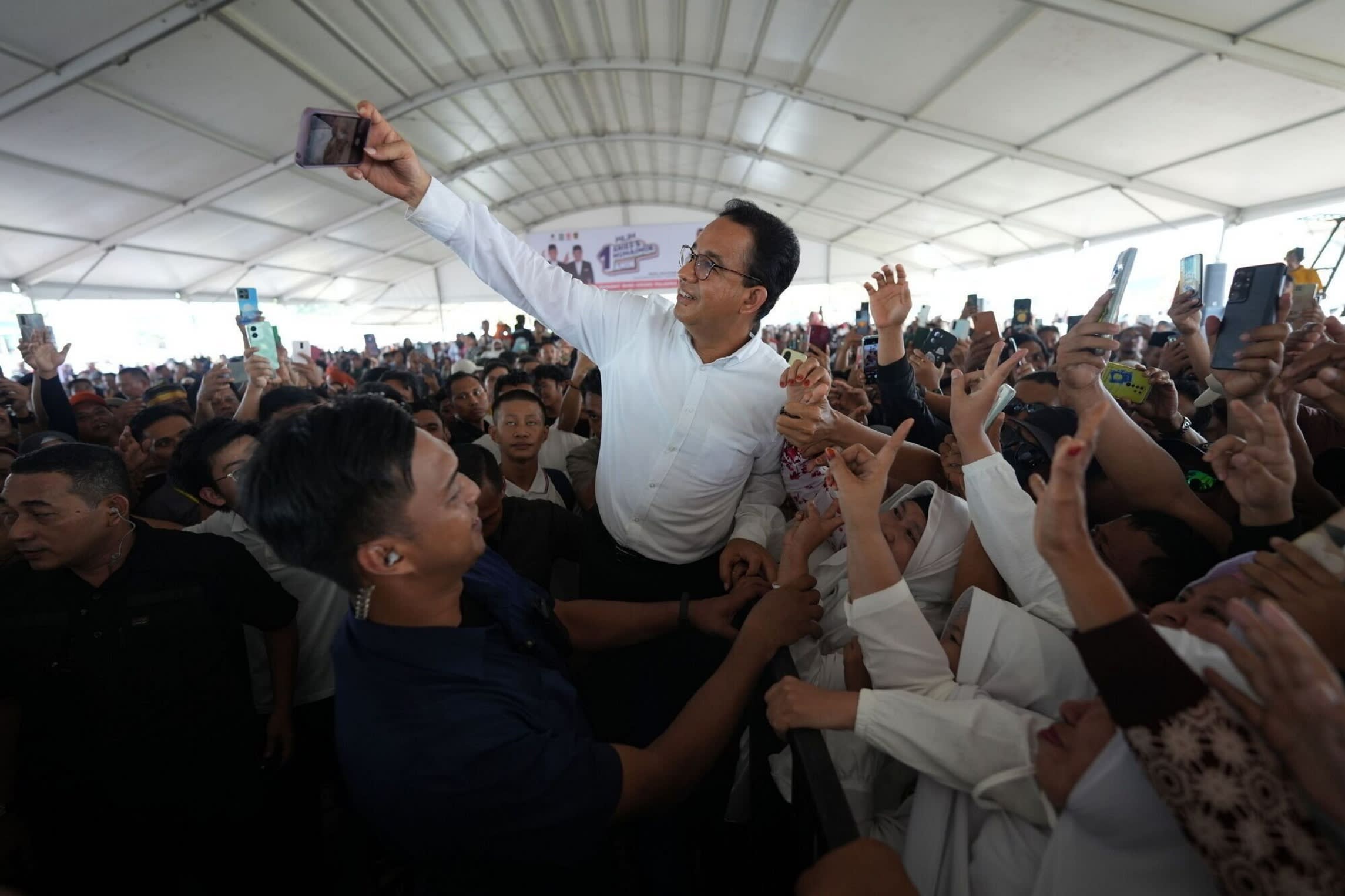 Anies Baswedan takes a photo with supporters during a campaign rally last week
