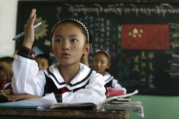 ENG_TIB_TibetanChildrenSupplementaryClasses_01082024.4.jpg A girl raises her hand to answer a question during a Tibetan language class at the Lhasa Experimental Primary School in Lhasa, capital of western China's Tibet Autonomous Region, June 19, 2009. (Greg Baker/AP)