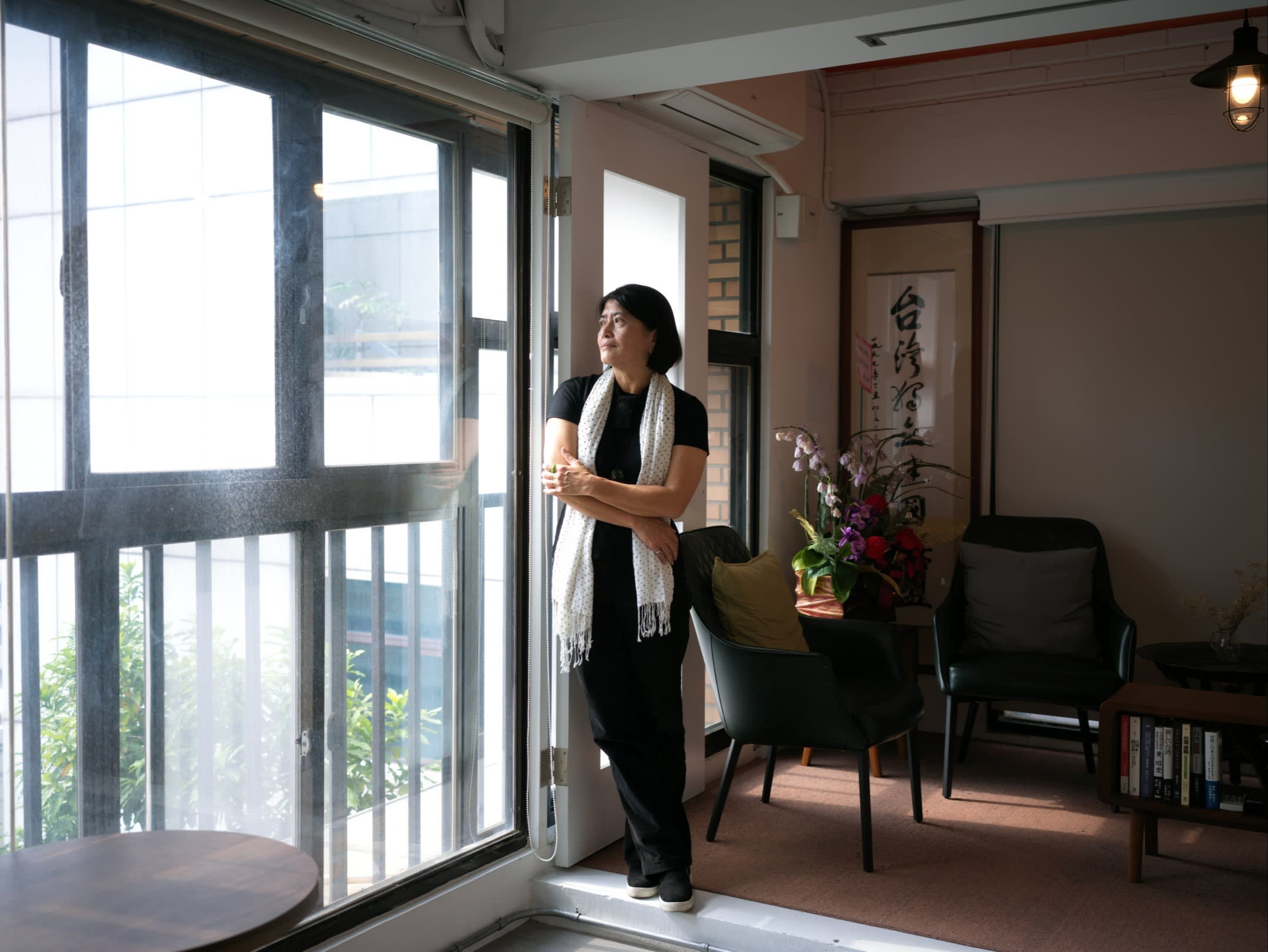 Hsieh Jolan stands in an apartment, gazing out of the full-length window
