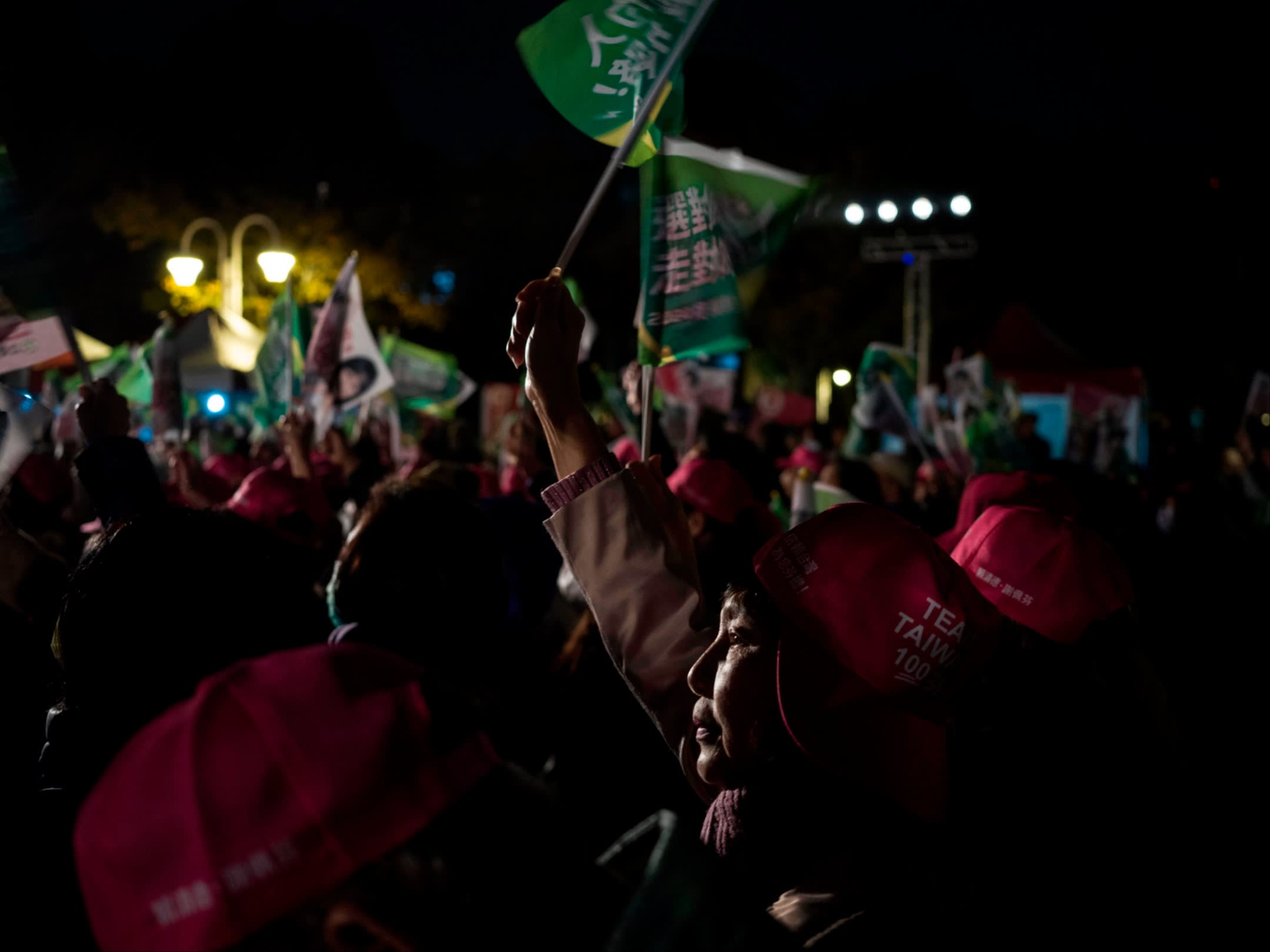 A woman holds up a flag at a nighttime rally