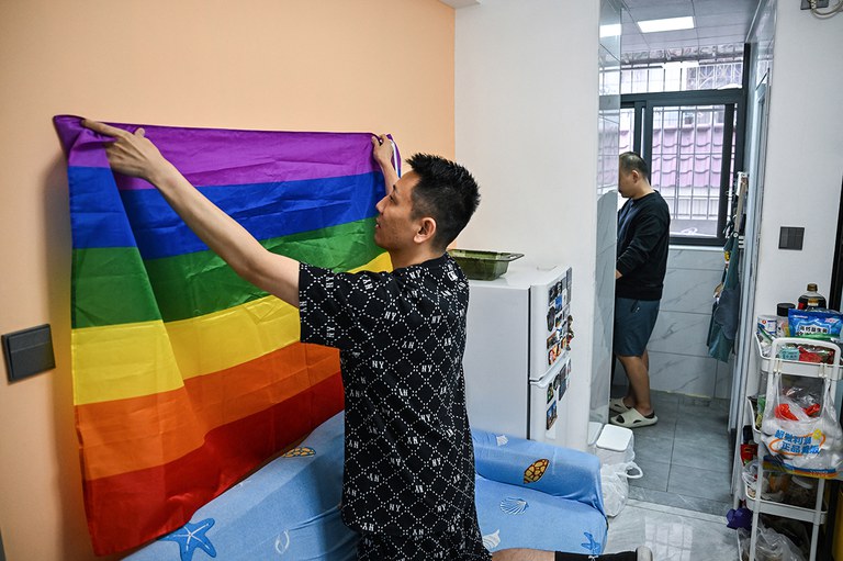 ENG_CHN_FEATURERainbowFlag_01252024.3.jpg .JPEG Willy (left) from Taiwan and Louis, from mainland China, in their apartment in Shenzhen, Guangdong, December 16, 2023. Willy hangs the rainbow flag, a symbol of the LGBTQ community, behind their sofa. (Hector Retamal/AFP)