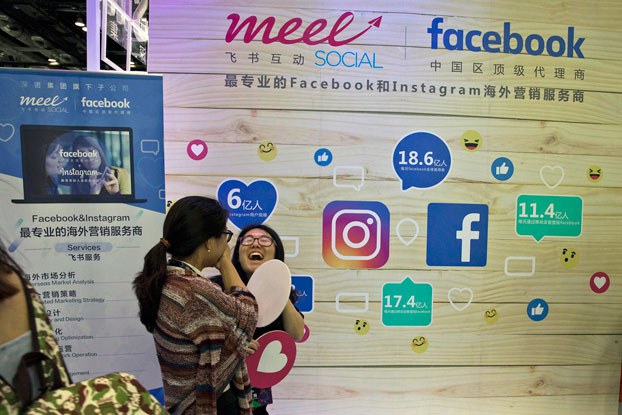 ENG_CHN_FEATURE30YearsOfInternetCensorship_01112024.4.jpg A woman reacts near a booth promoting overseas marketing services on Facebook and Instagram, which are banned in China, during an internet conference in Beijing in 2017. (Ng Han Guan/AP)