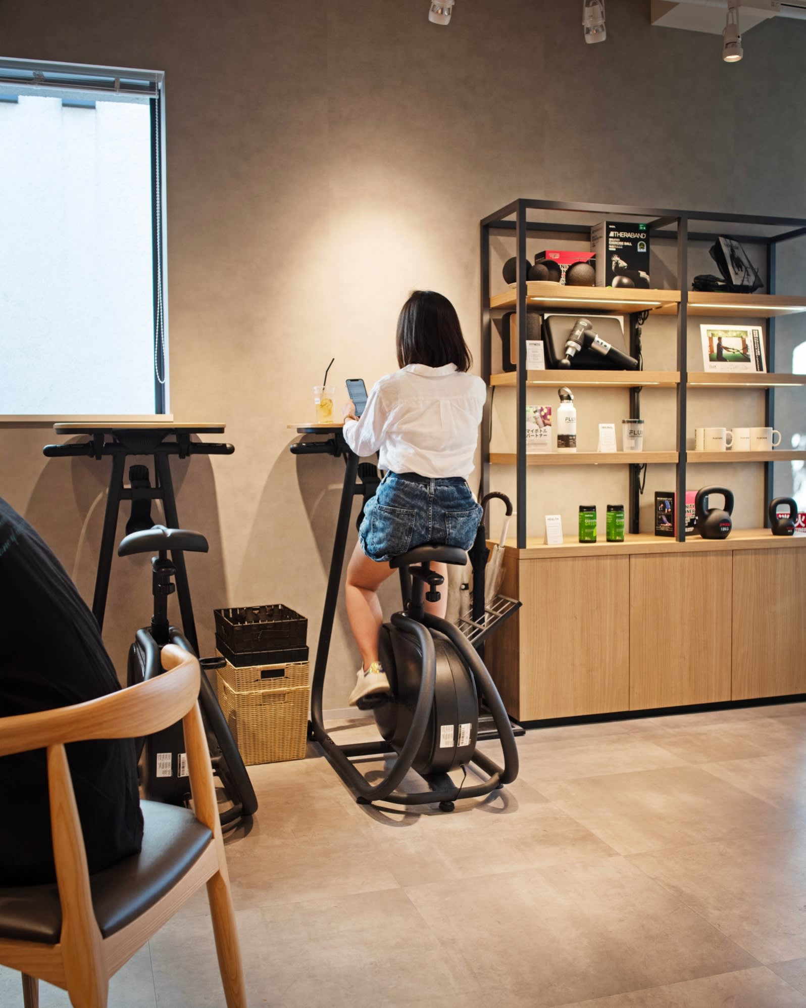 A woman scrolling through her phone while sitting on a gym bike at Flux Café
