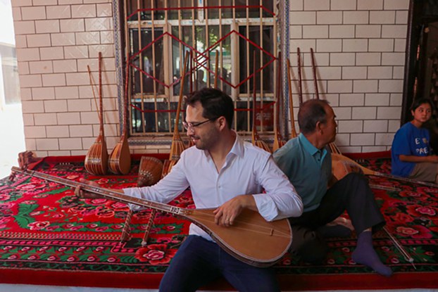 ENG_UYG_TravelJunkets_01112024.3.jpg Hector Dorbecker, counselor for economic-commercial and financial affairs at the Embassy of Mexico in Beijing, tries to play dutar, a long-necked two-stringed lute, in Jiayi village of Xinhe county in northwestern China's Xinjiang region, Aug. 2, 2023. (Zhao Chenjie/Xinhua via Getty Images)
