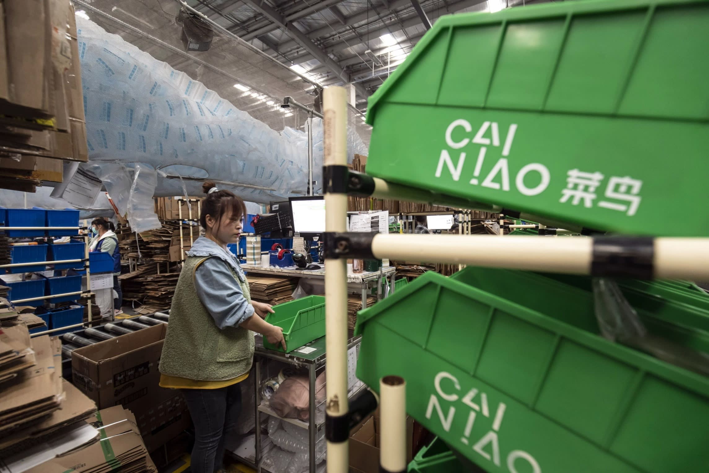 Employees work at packaging stations at a Cainiao warehouse