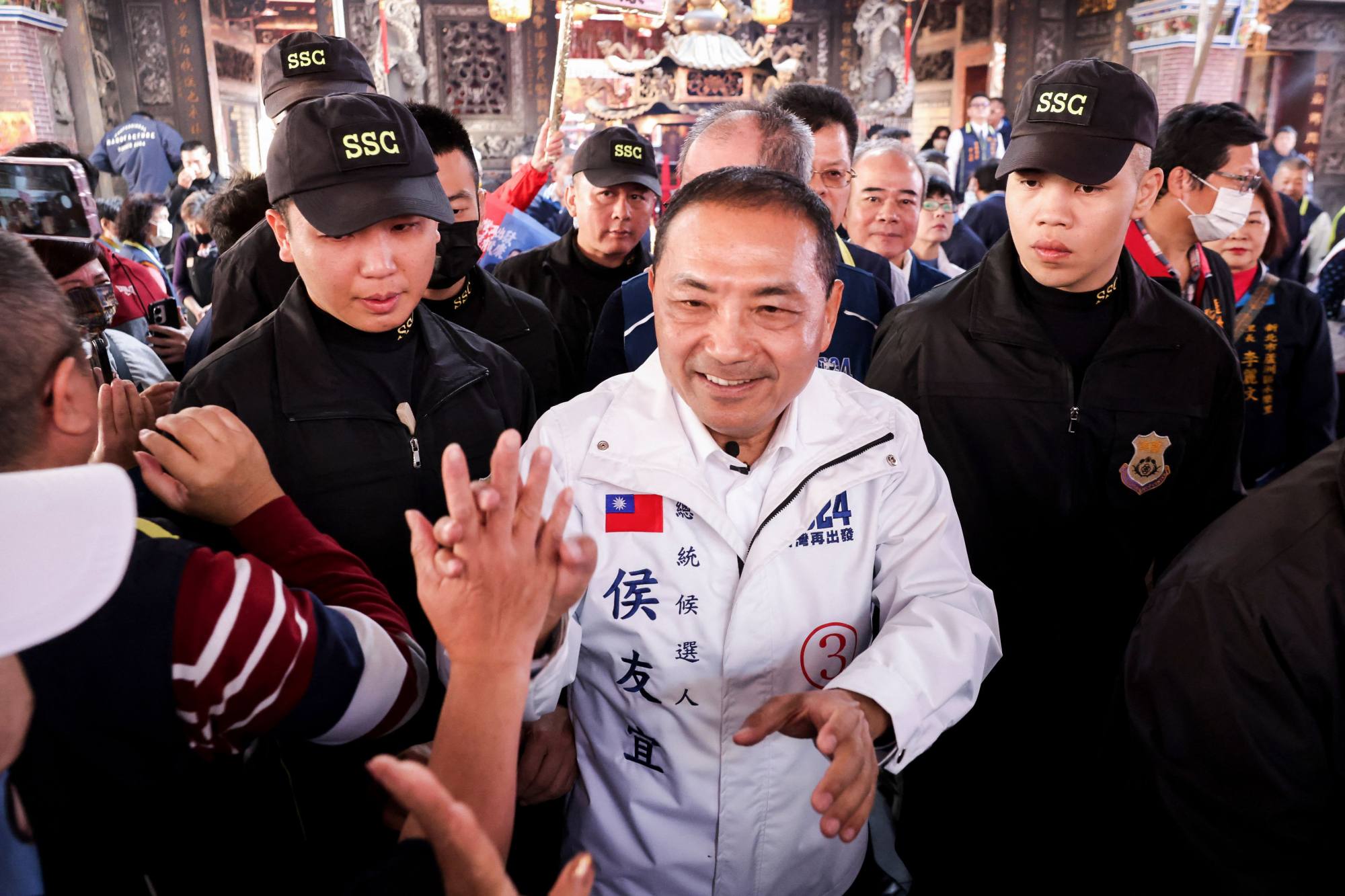 Opposition KMT candidate Hou Yu-ih shakes hands with supporters at a temple in New Taipei City. Photo: AFP