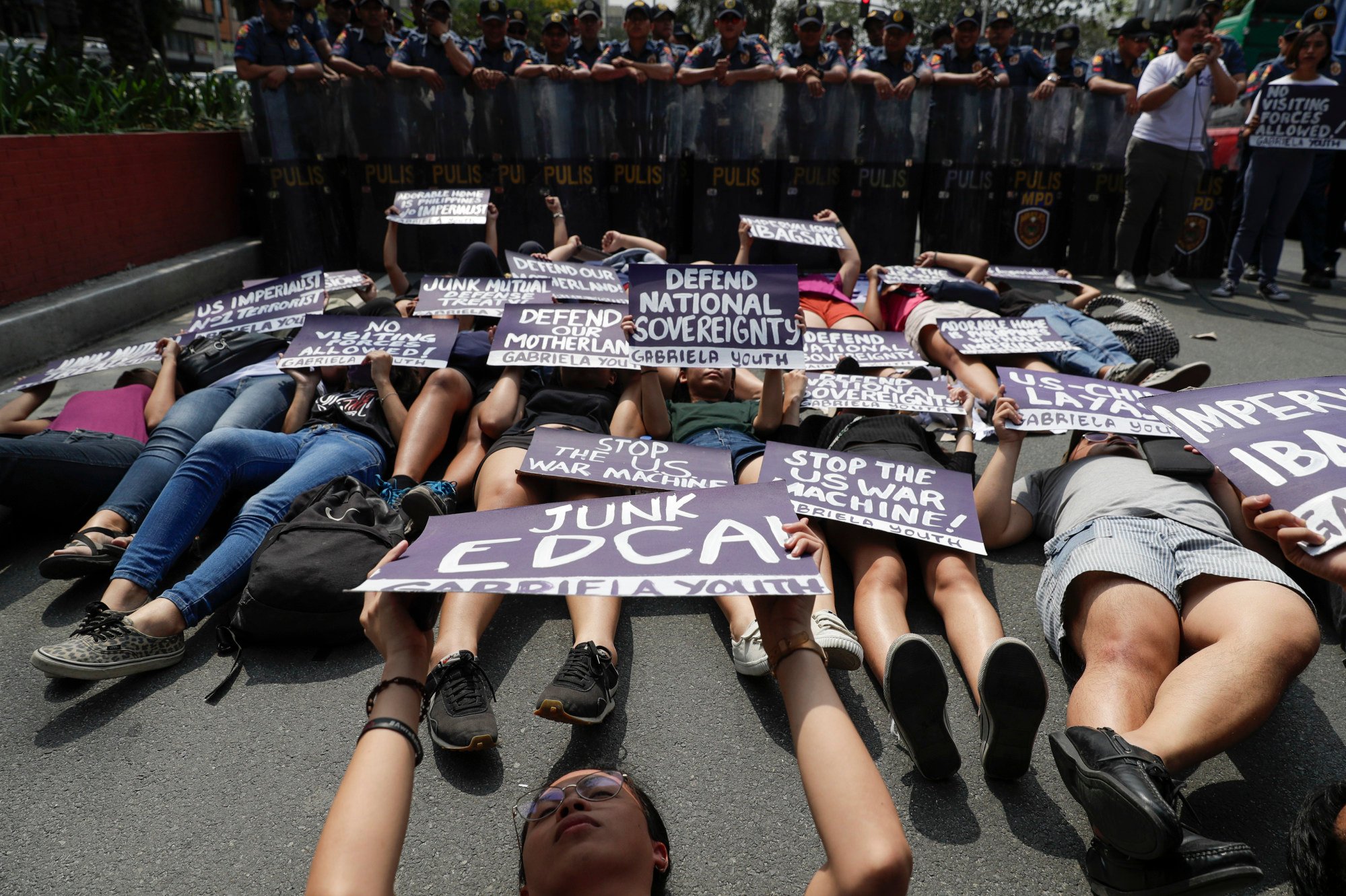 Women protesters lie in front of a police blockade during a rally outside the US embassy in Manila, Philippines, on March 6, 2020. The group called on the government to immediately stop the planned military exercises between the Philippines and US under the Visiting Forces Agreement. Photo: AP