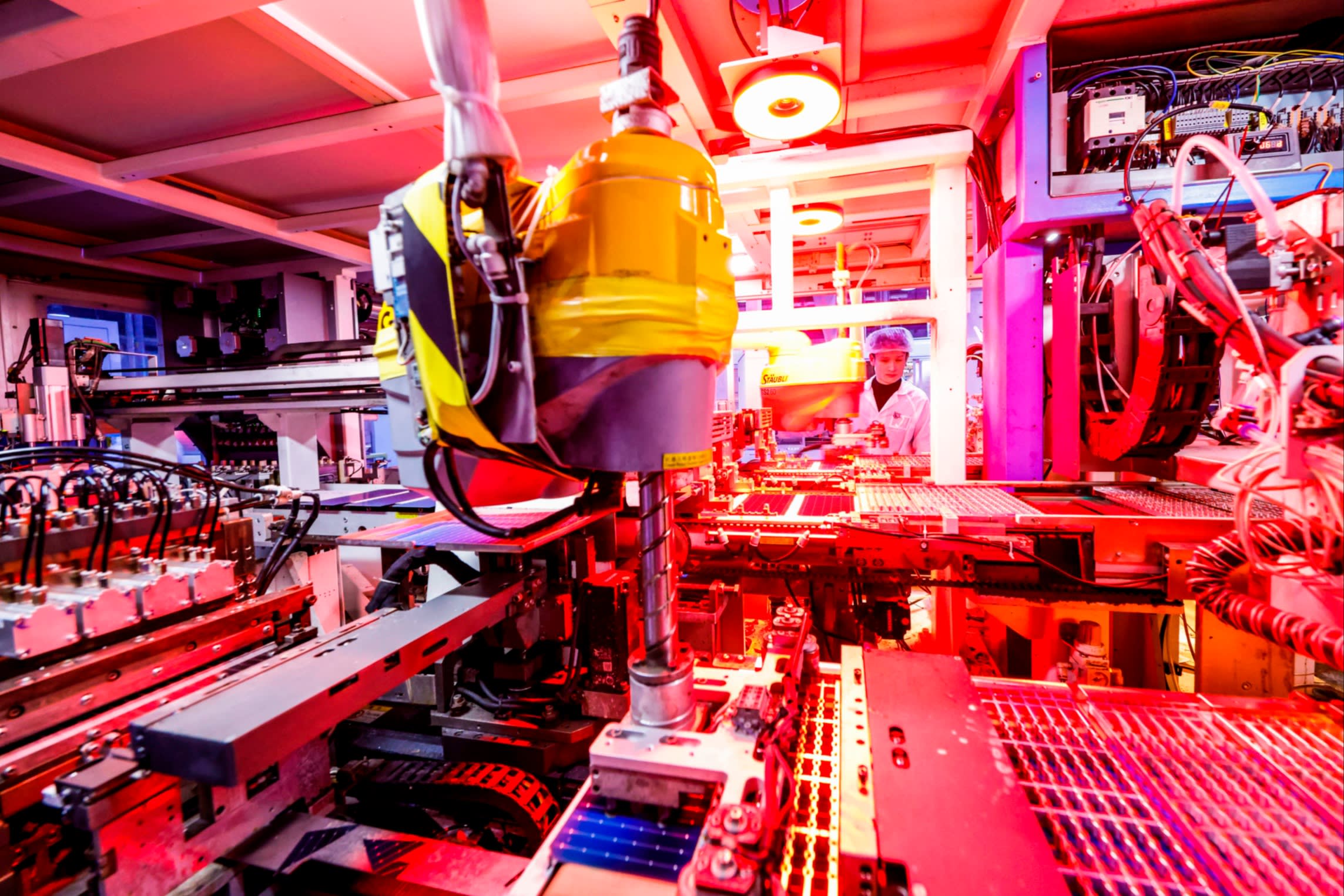 A worker in China operates a machine producing solar panels for export