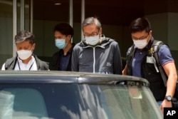 FILE - Police officers escort Cheung Kim-hung, publisher of Apple Daily, from the tabloid's headquarters in Hong Kong on June 17, 2021.