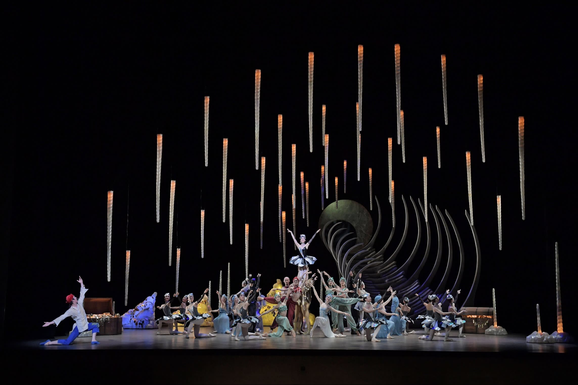 The cast of David Bintley’s ‘Aladdin’ on stage, with illuminated orange rods hanging above them