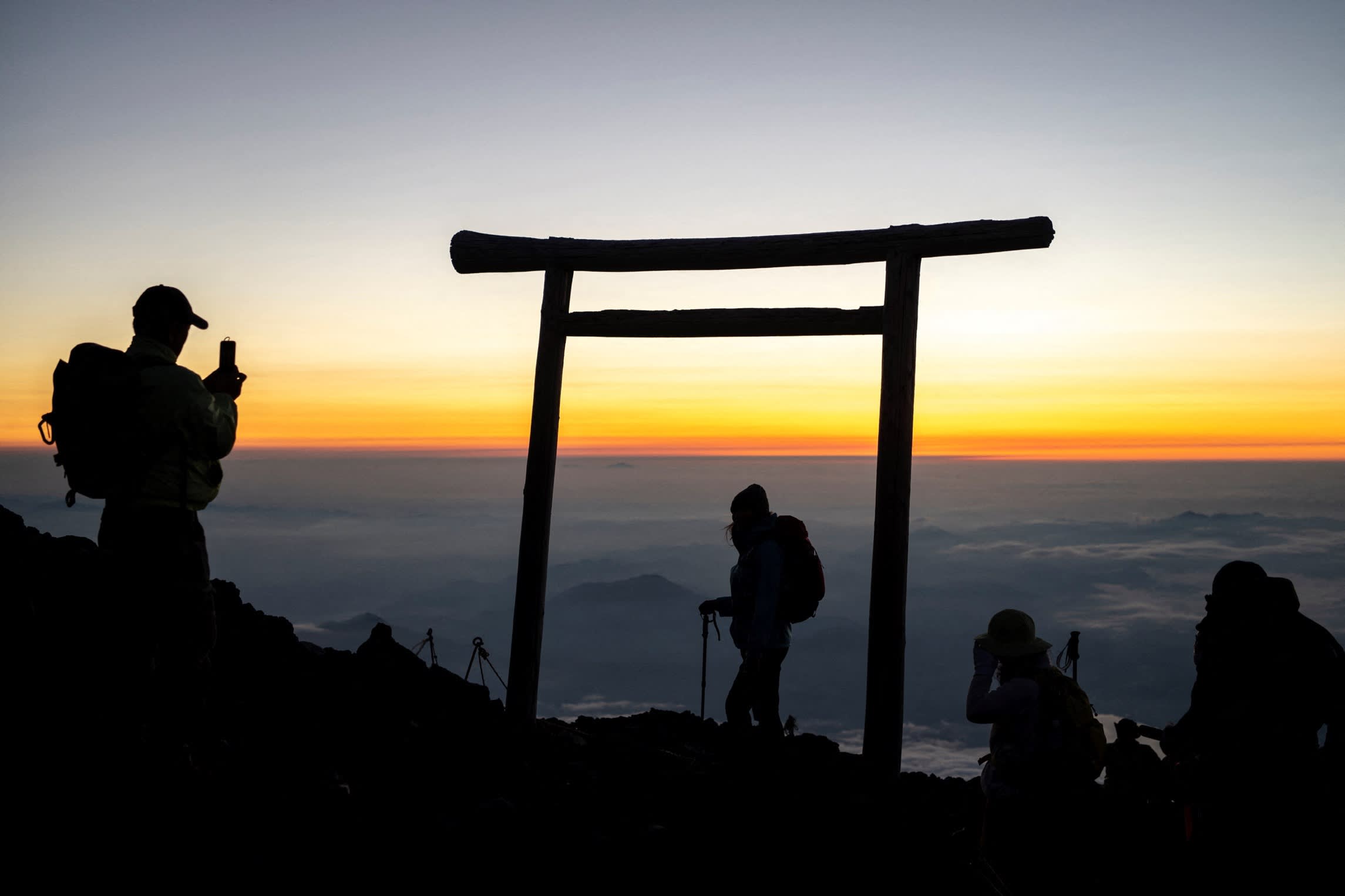 Hikers watching the sunrise from the peak of Mount Fuji