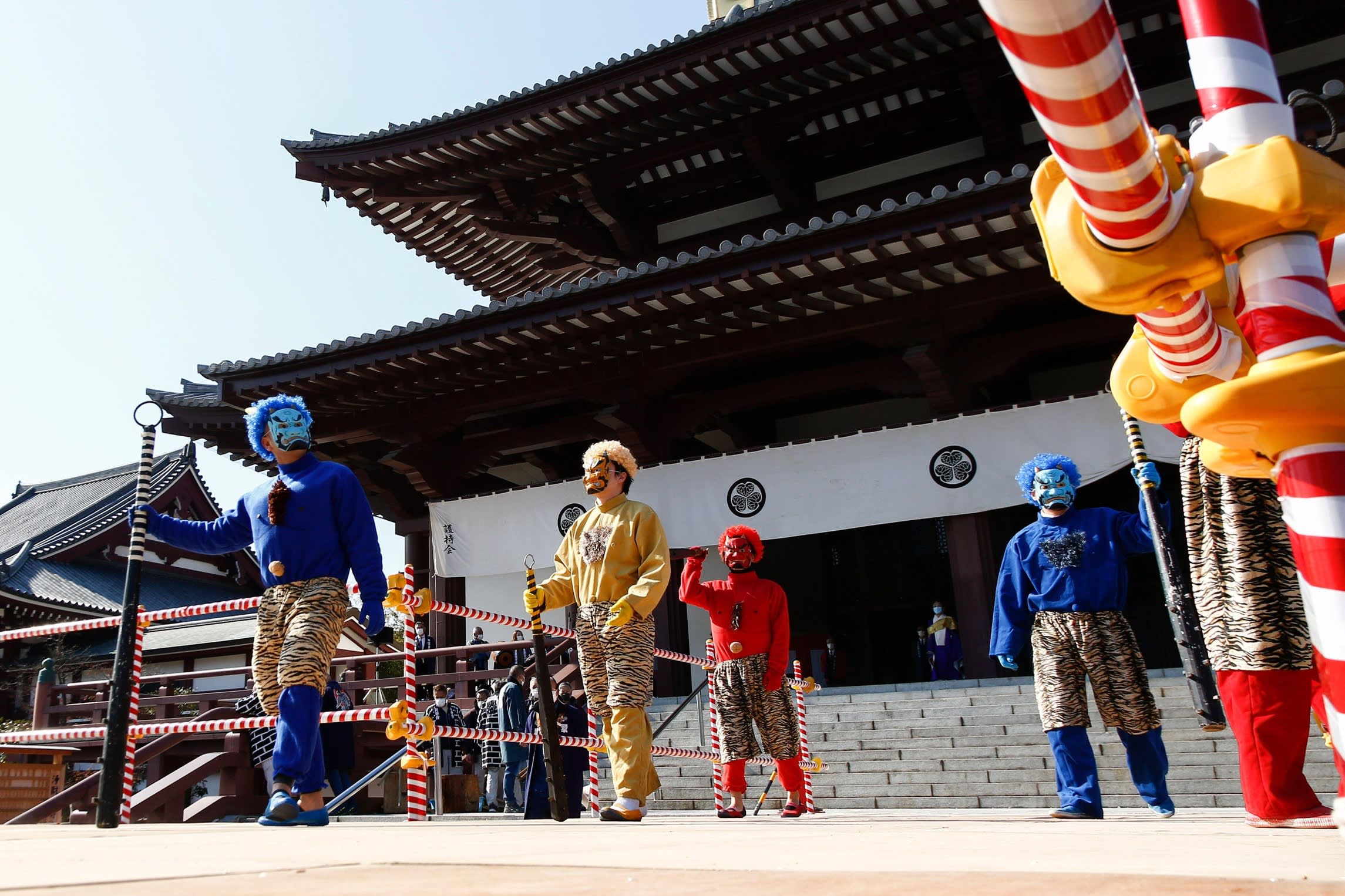 Men wearing colourful Japanese ogre masks and holding long clubs during Setsubun celebrations at Tokyo’s Zojoji Temple