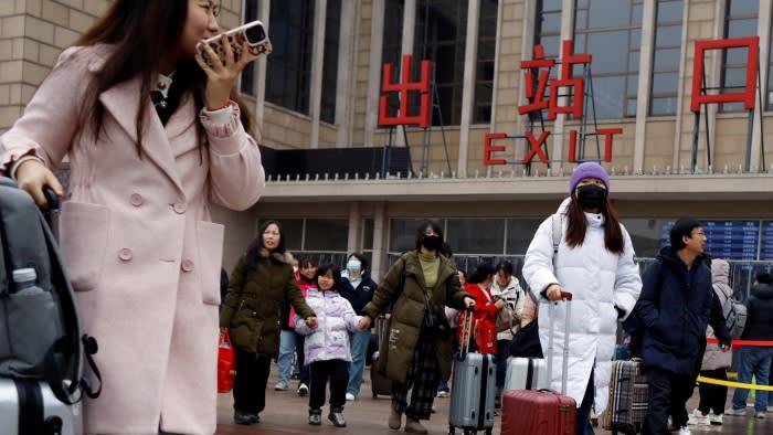 Travellers walking with luggage outside Beijing train station