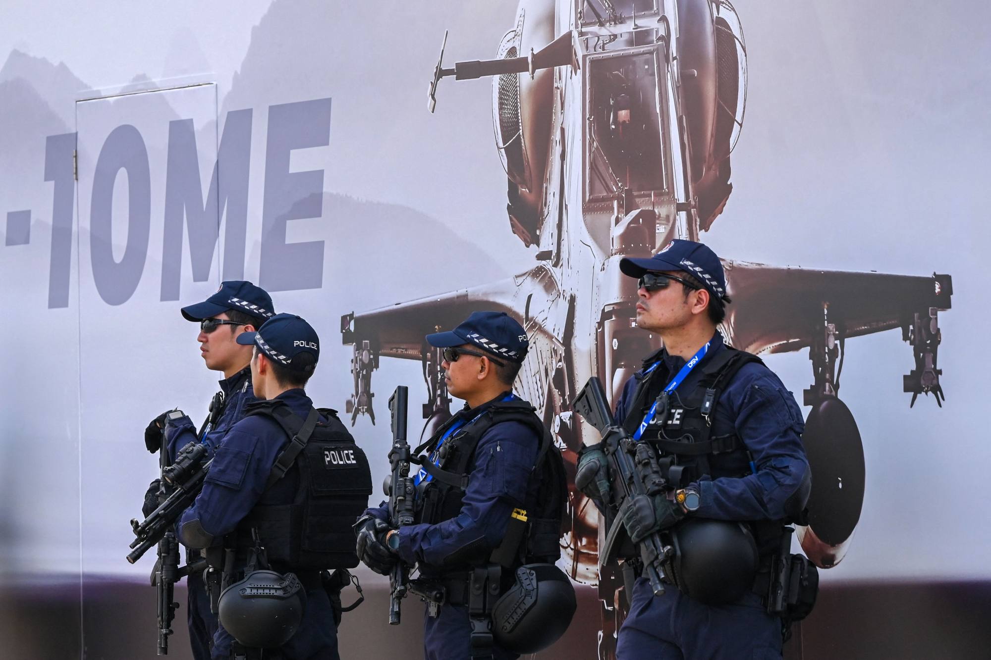 Armed Singapore police stand in front a poster of China’s Z-10ME helicopter at the air show. Photo: AFP
