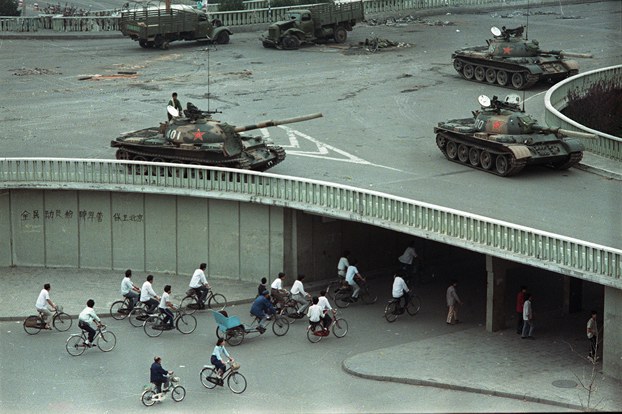 ENG_CHN_INTERVIEWFrankDikotter_02222024.6.jpg Bicycle commuters pass under an overpass where Chinese army tanks are positioned in Beijing, two days after the Tiananmen Square massacre, June 6, 1989. (Vincent Yu/AP)
