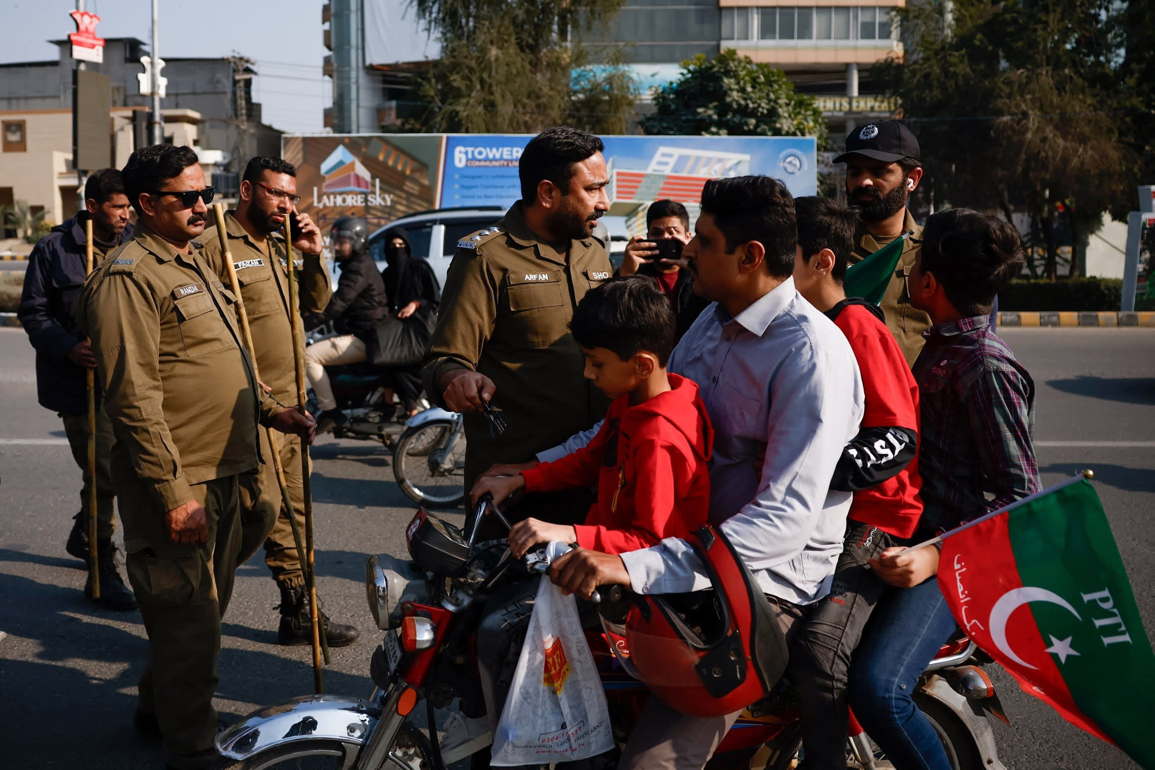 Police officers stop PTI supporters displaying the party’s flag in Lahore on Sunday