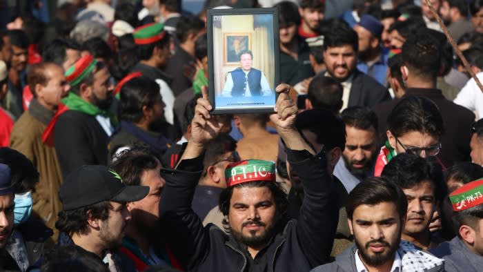 A man holds aloft a photograph of Imran Khan