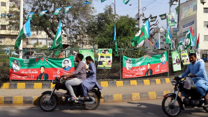 People drive past electoral posters of jailed former Prime Minister Imran Khan