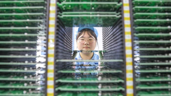A Chinese woman handles circuit boards in a factory