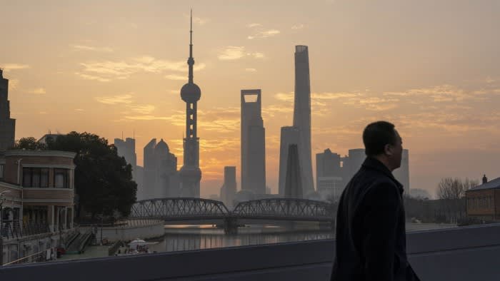 A man walks past the buildings of Shanghai’s financial district at dusk