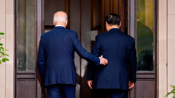 Rear view of Joe Biden with his hand touching Xi Jinping’s back as he ushers him through a door