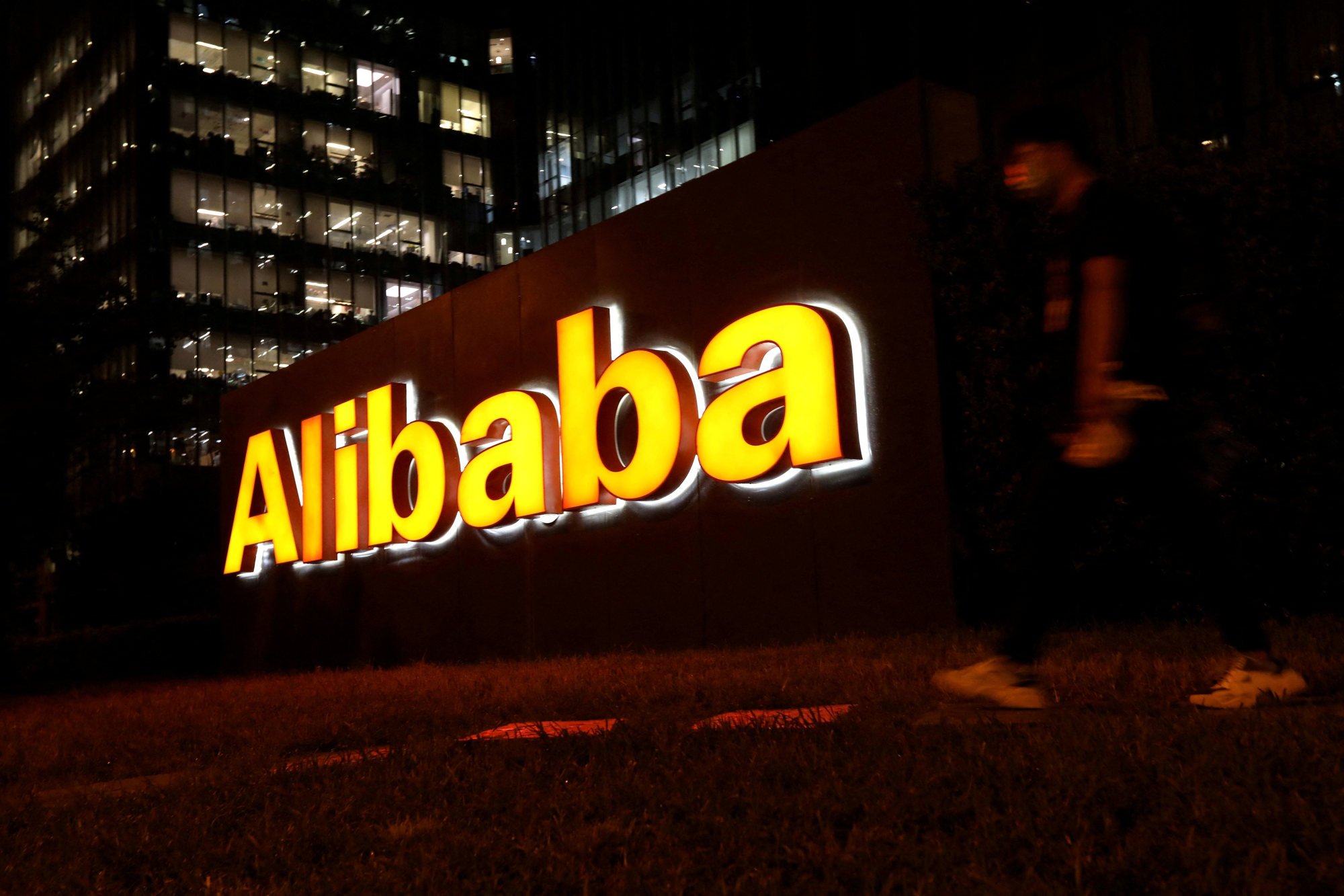 A man walks past Alibaba’s logo at its office building in Beijing, August 9, 2021. Photo: Reuters
