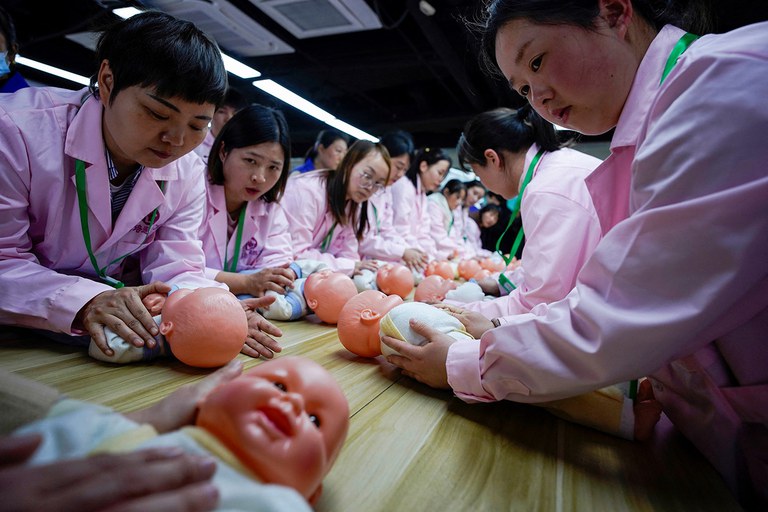 ENG_WOMEN'S_Analysis_03072024.2.JPG Women train with plastic baby dolls as they take part in a nursing skills class at Yipeitong training center in Shanghai, March 2, 2023. (Aly Song/Reuters)