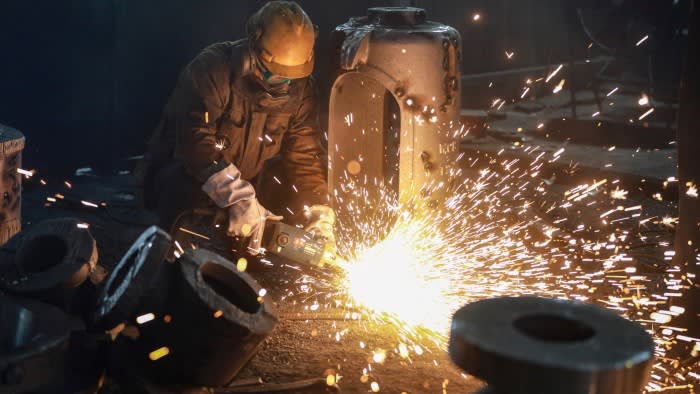 Sparks fly as the worker, in protective clothing, works the metal