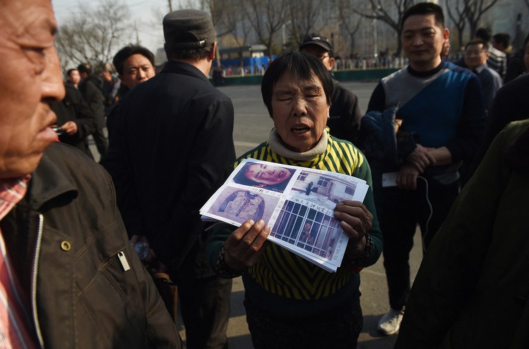 ENG_CHN_FEATURESensitiveDates_03132024.3.jpg A petitioner holds photos of evidence in her grievance against local officials, outside a government petition office in Beijing on March 2, 2016, a few days before the National People's Congress opens its annual session. (Greg Baker/AFP)