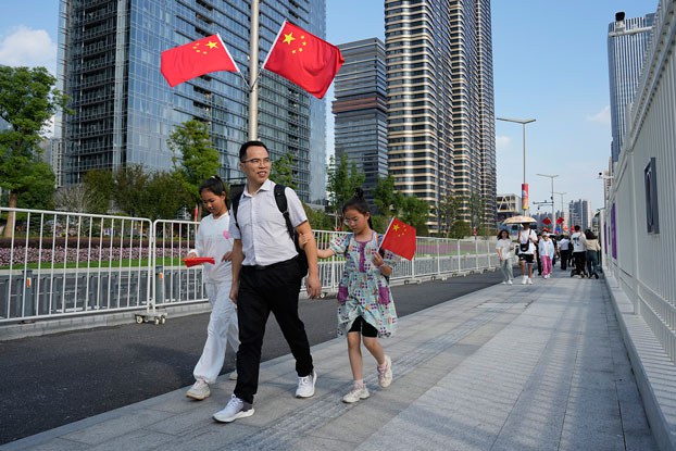 ENG_CHN_WOMENSDAYBirths_03072024.3.jpg A family walks with Chinese flags as the country marks its 74th National Day in Hangzhou, China, Oct. 1, 2023. (Aaron Favila/AP)