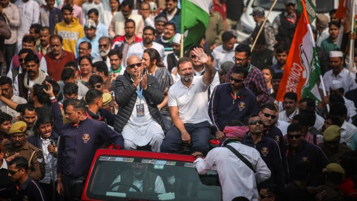 Gandhi waves while sitting on the roof of a red jeep