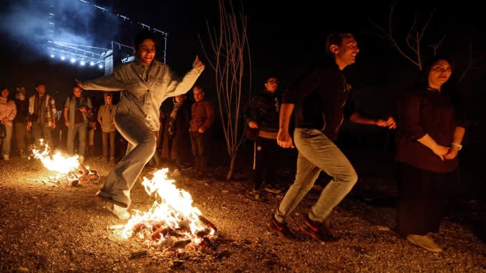 People dance around an open fire
