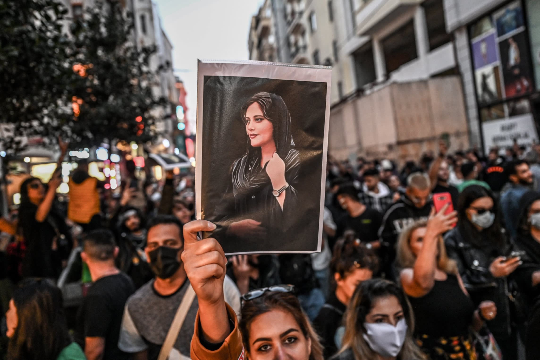A protester holding a portrait of Mahsa Amini at a march