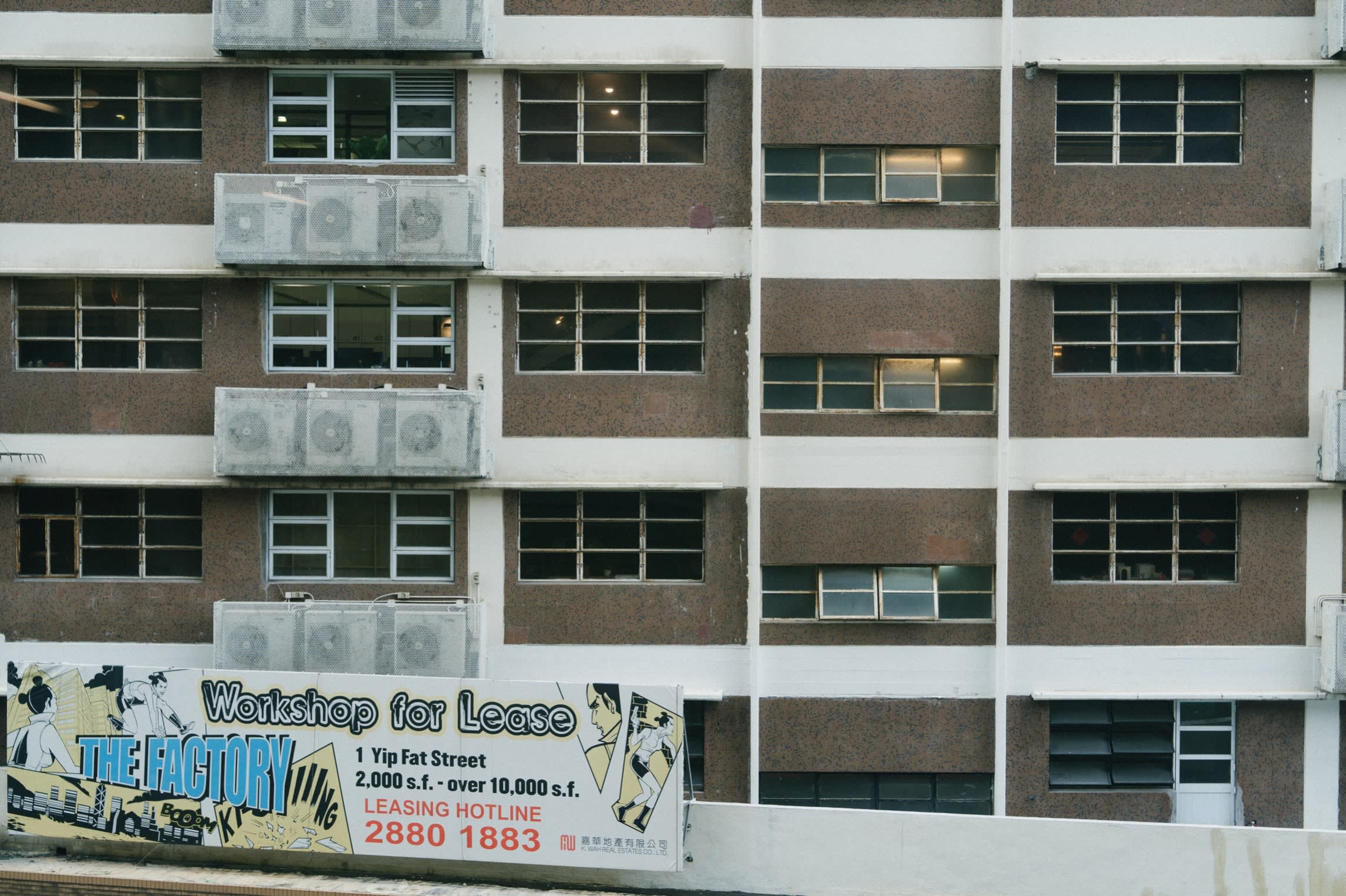 View of a depressing industrial building. A sign on the front says ‘Workshop for Lease’