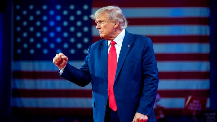 Donald Trump holds up a clenched fist in front of a giant US flag