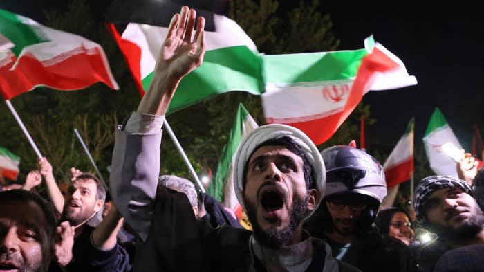 Demonstrators in Tehran wave Iran’s flag and Palestinian flags after Iran launched a drone and missile attack on Israel