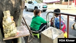 Lun Sam Ath, 45, with her son, Then Sithet, 10, sells face masks on a street in Phnom Penh, capital of Cambodia, April 5, 2024 (Sun Narin/VOA Khmer)