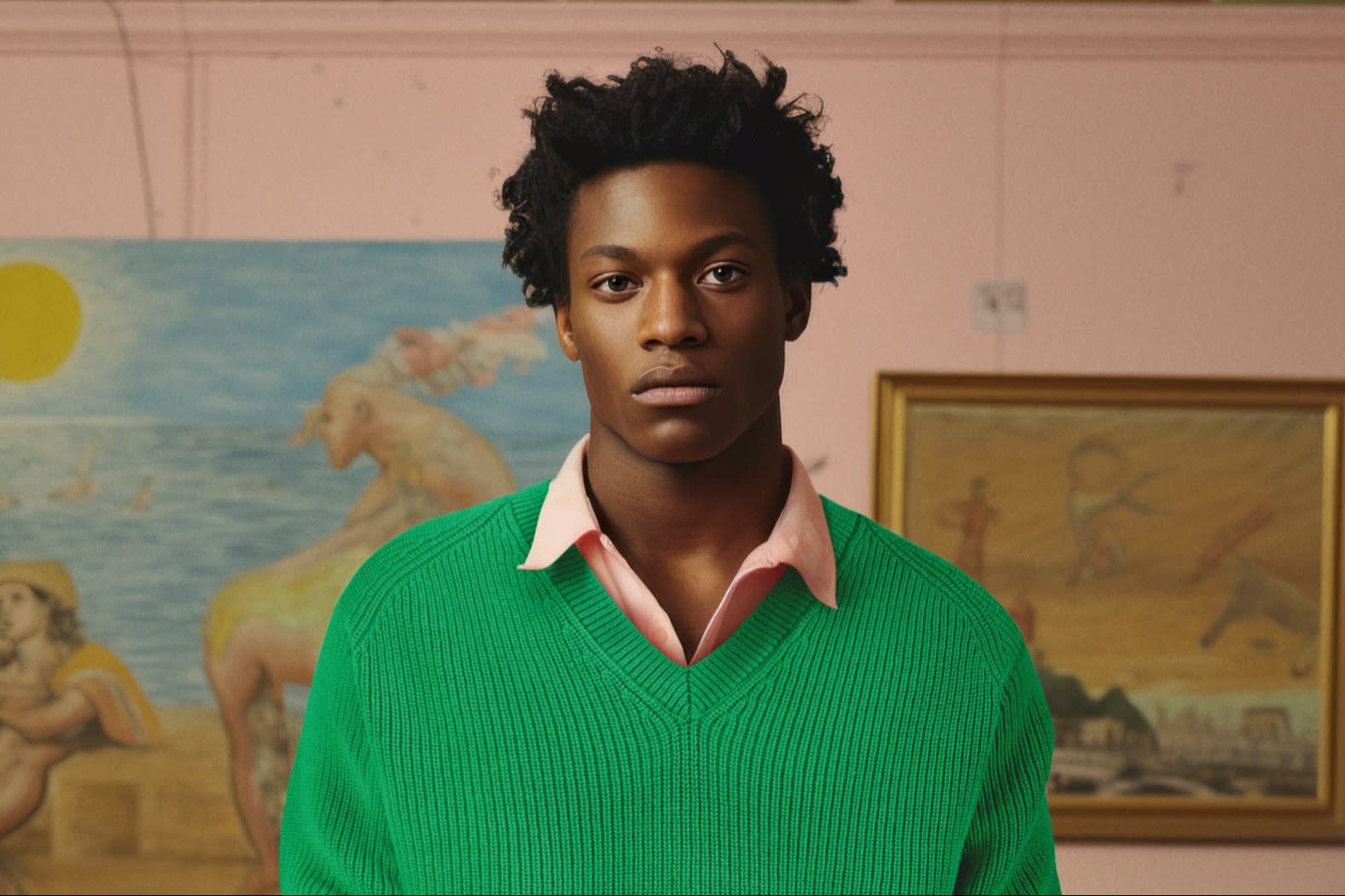 A man wears a bright green sweater over a pink shirt