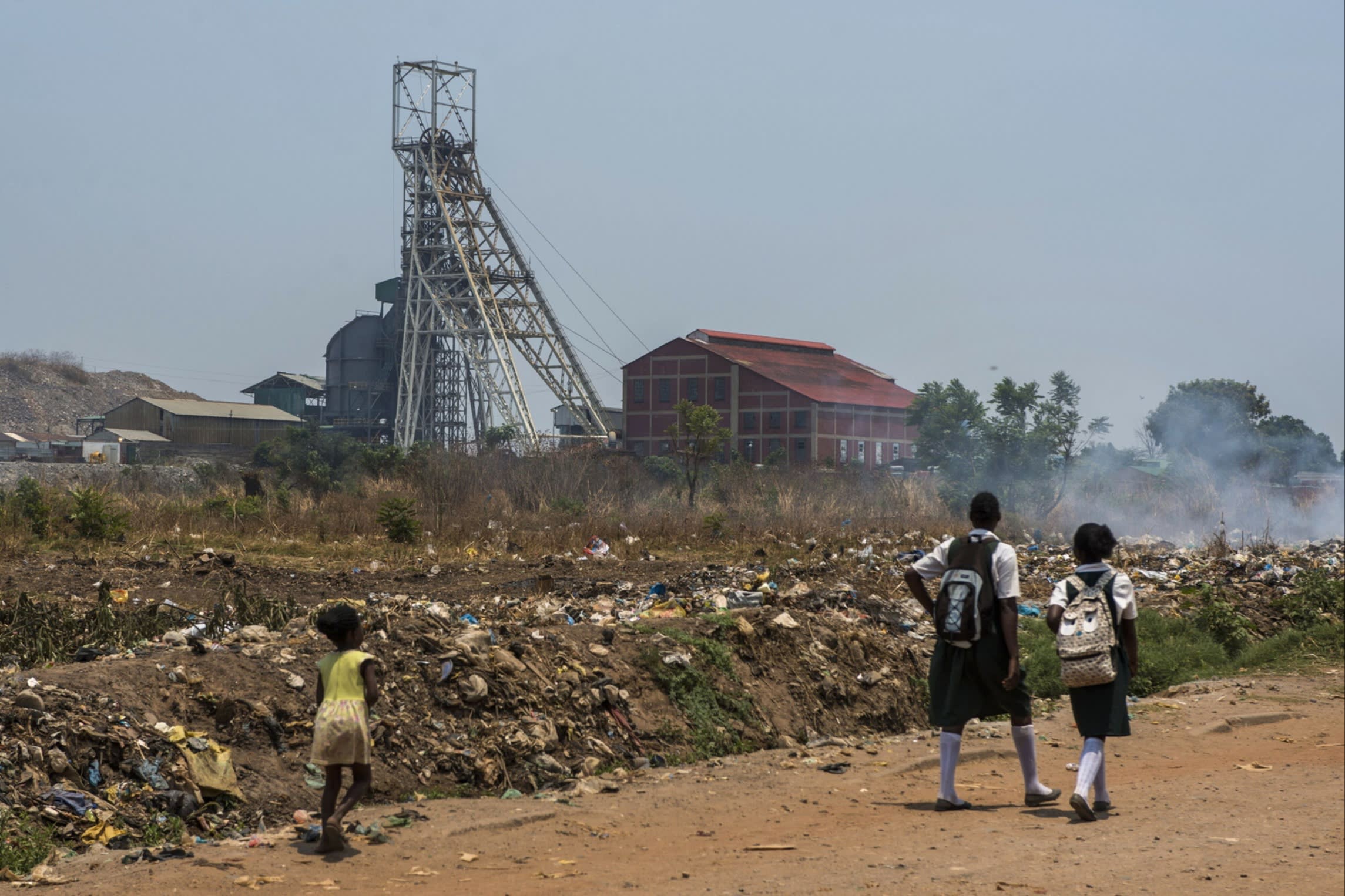 Schoolchildren walk past part of the Mopani copper mine site in Kitwe, Zambia