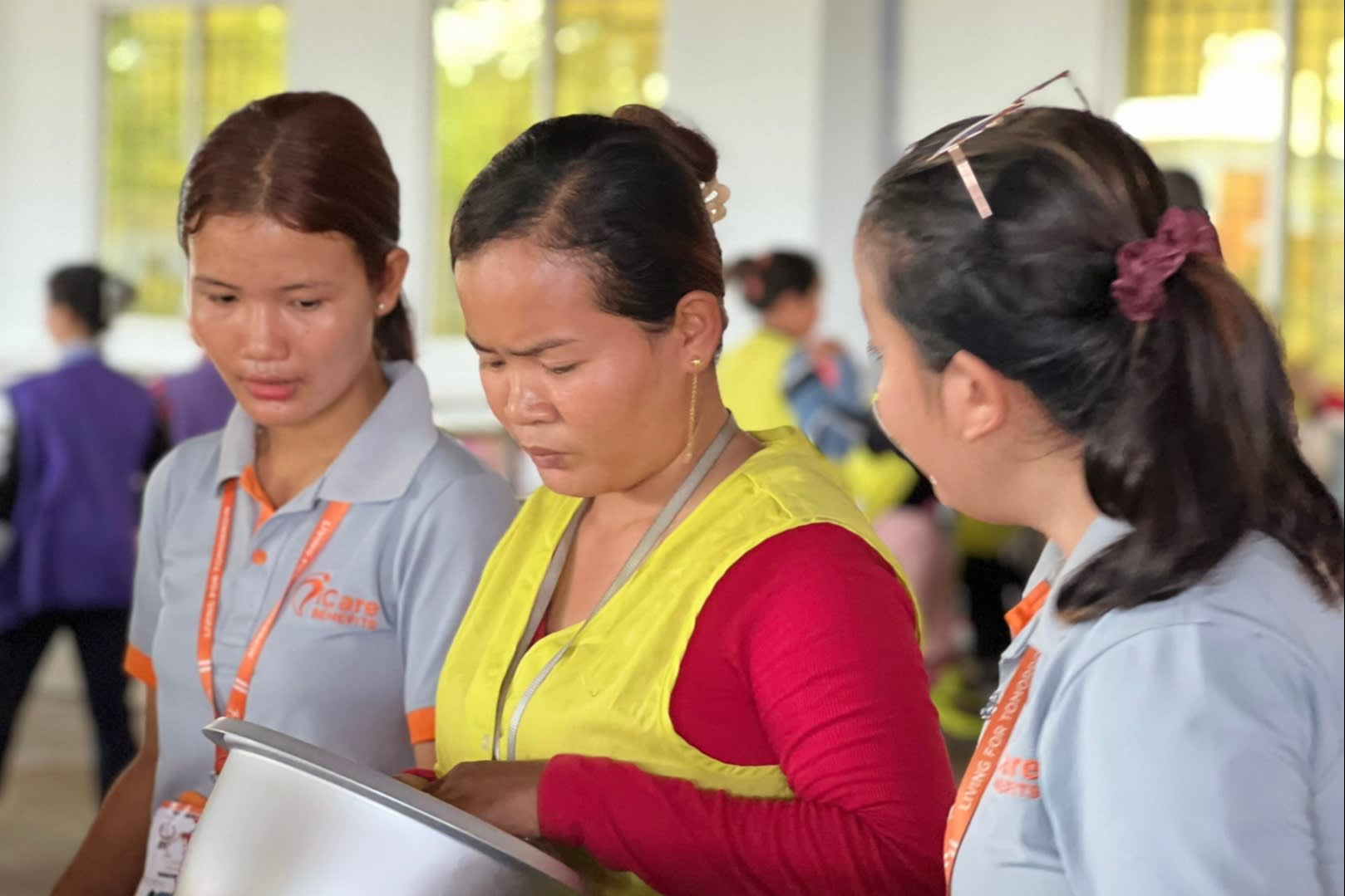 A female customer inspecting a rice cooker as two store employees look on
