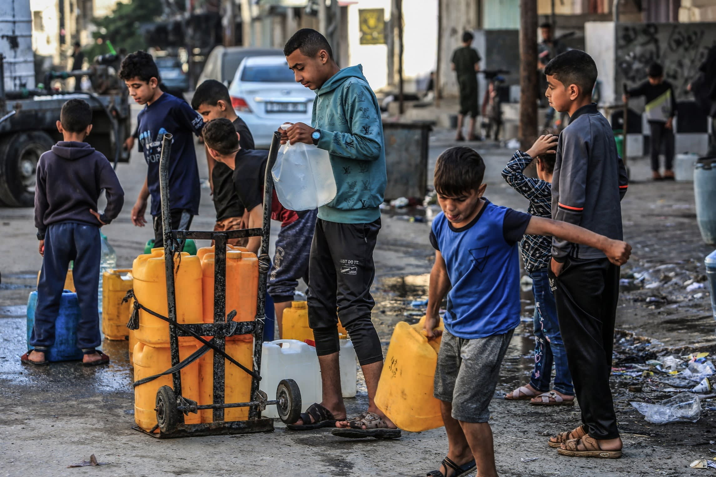 Palestinians, including children, fill containers with drinking water