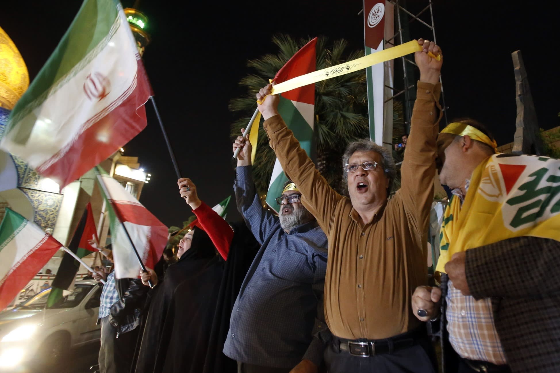People hold Iranian and Palestinian flags during an anti-Israel rally after Iran launched drone attacks against Israel at Palestine Square in Tehran