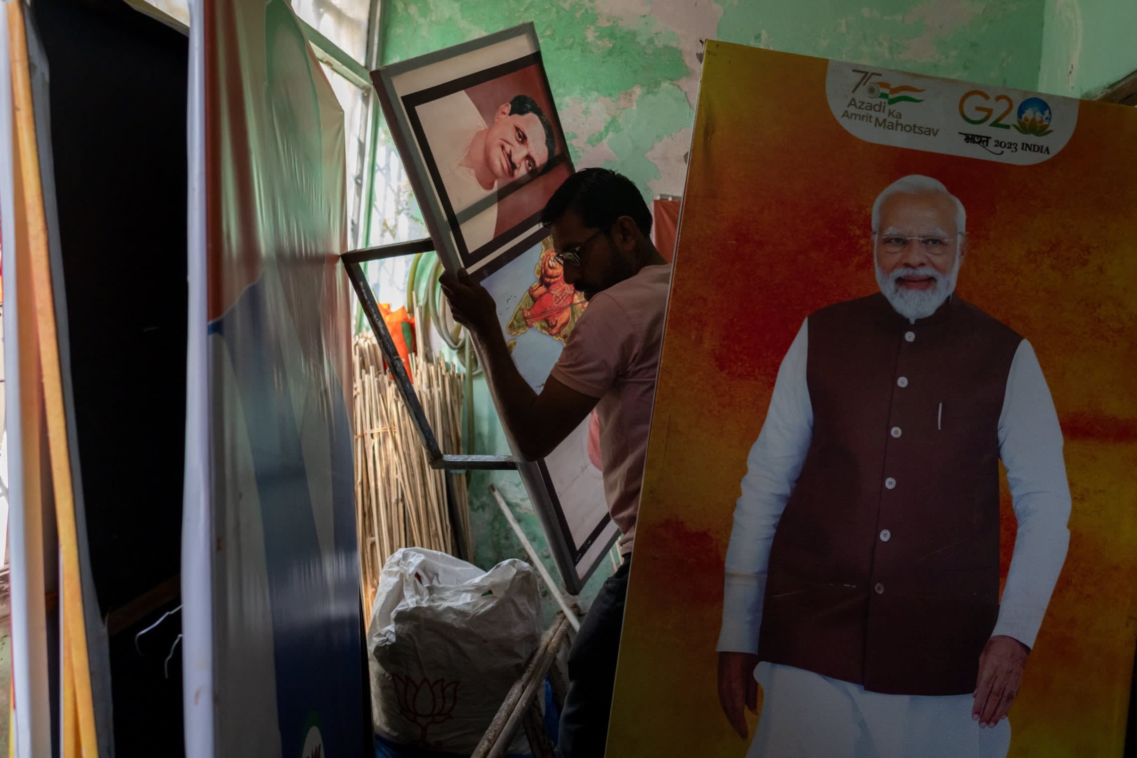 A BJP worker in Bhopal gathers party paraphernalia next to a painting of Narendra Modi. Welfare has been a central part of the prime minister’s appeal among India’s hundreds of millions of poor and marginalised people
